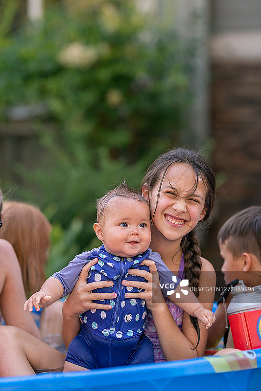 自豪的小学女生在儿童泳池里抱着小妹妹图片素材