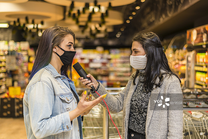新闻频道记者在购物中心采访一位女士。新冠疫情图片素材