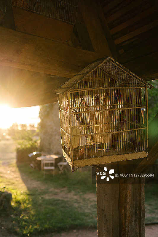 日落逆光下的空复古鸟笼图片素材