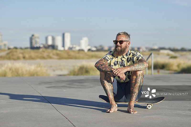 坐在城市滑板上的时髦青年图片素材