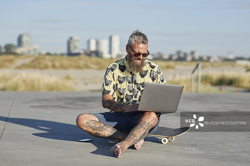 在城市里使用滑板上的笔记本电脑的男人图片素材