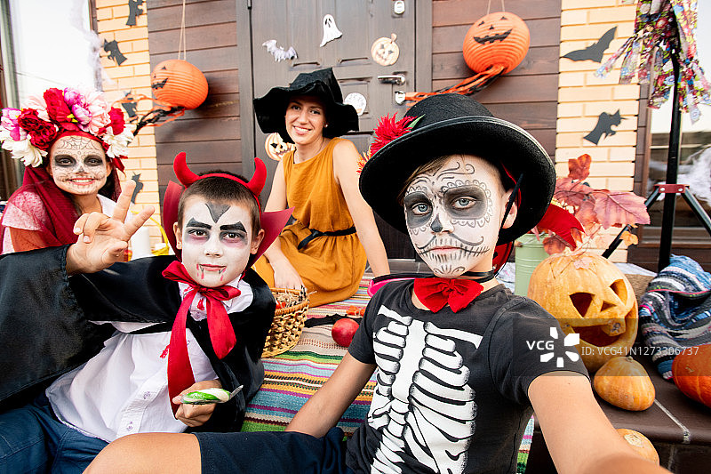 两名男孩和一名女孩画着脸，坐在快乐的年轻女性背景上图片素材