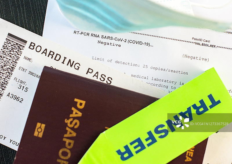 带有新型冠状病毒阴性RT-PCR核糖核酸检测结果、登机牌和医用口罩的护照图片素材