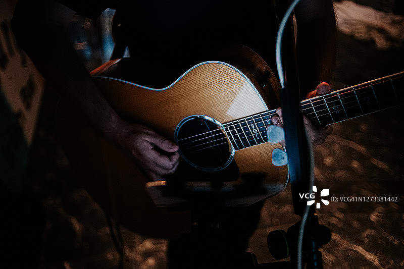 年轻男子弹奏原声吉他的暗调照片图片素材