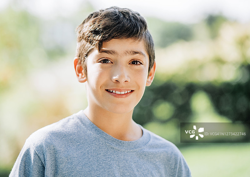 阳光明媚的日子里在后院里微笑的可爱男孩图片素材