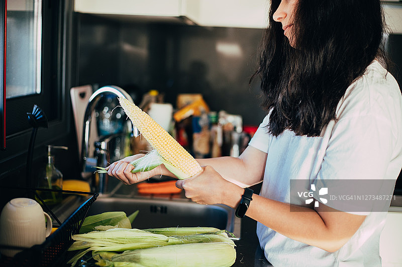 女人在厨房里剥玉米图片素材