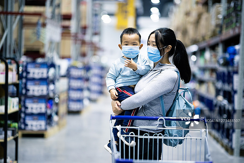 母亲和戴着防护口罩的婴儿在超市购物图片素材