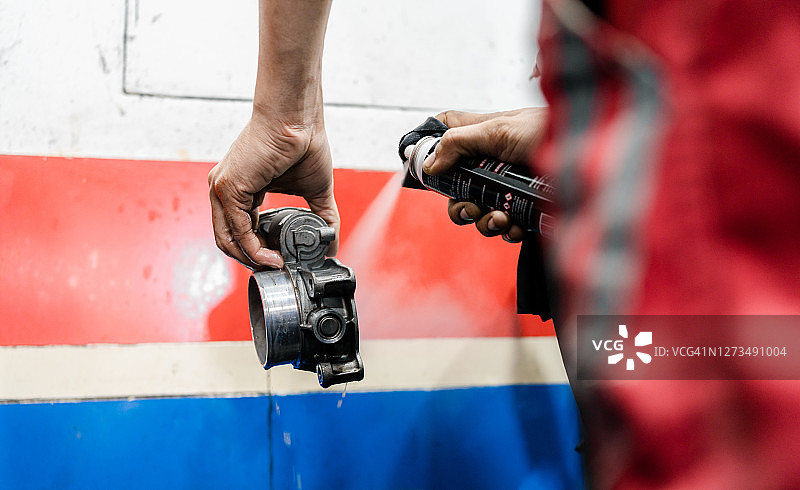 汽车修理店用喷雾清洗节气门的技工图片素材