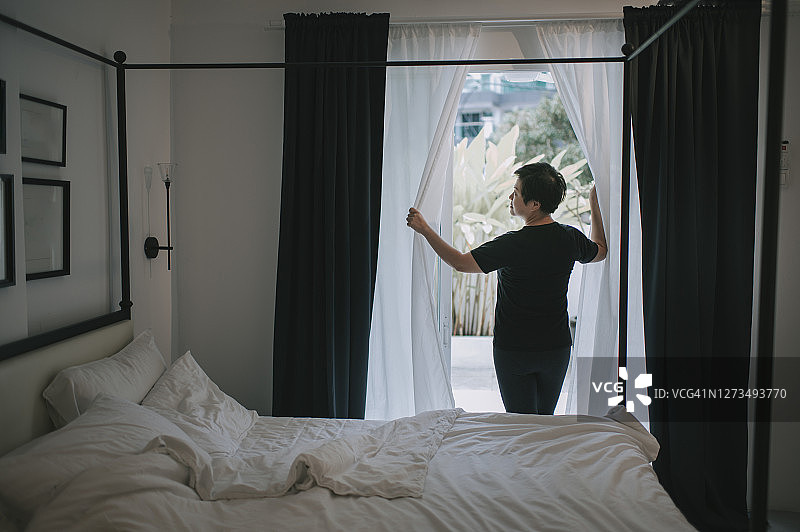 清晨，美丽的亚洲女子打开窗帘走向阳台，准备练习瑜伽图片素材