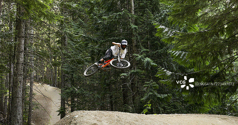 山地自行车手在森林环境中腾空跳跃图片素材