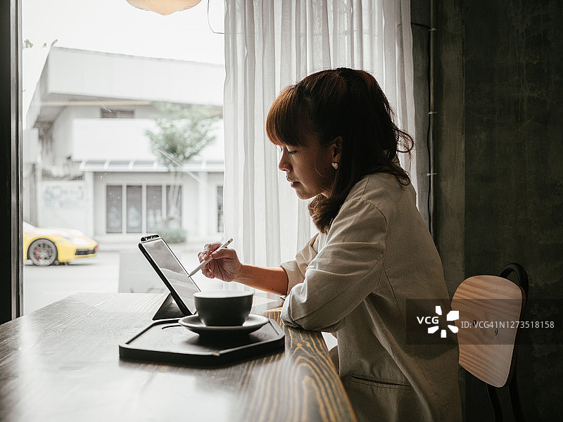 在咖啡馆使用平板电脑的亚洲女人图片素材