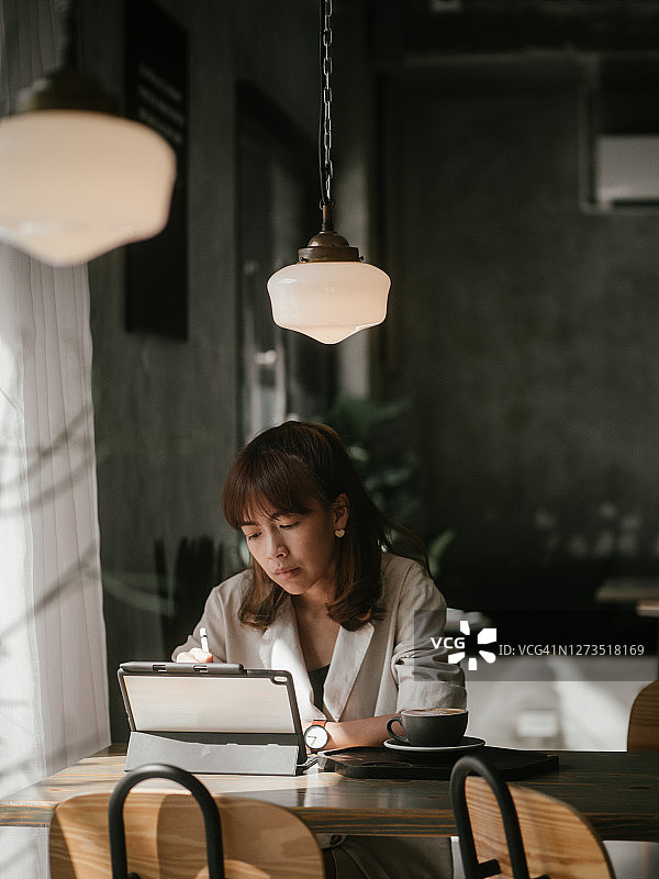 在咖啡馆使用平板电脑的亚洲女人图片素材