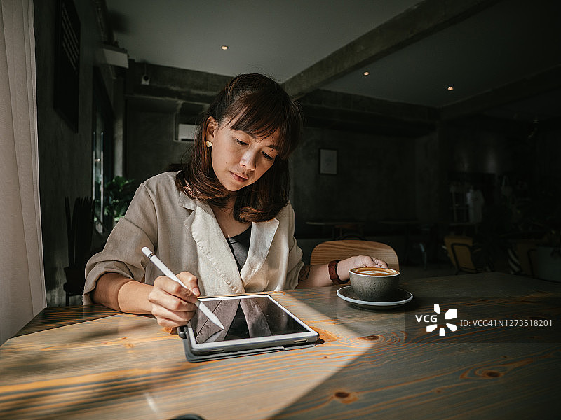在咖啡馆使用平板电脑的亚洲女人图片素材