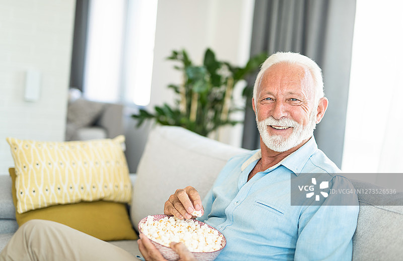 年长的男人在家放松地吃着爆米花图片素材
