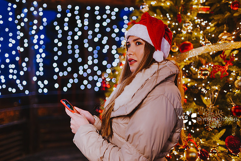 在圣诞树前使用手机的女人图片素材