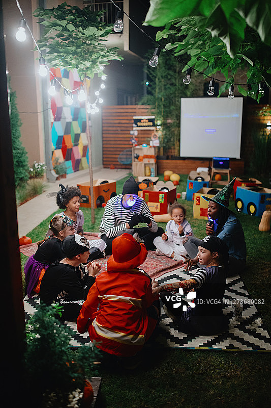 父母在户外万圣节派对上给孩子们讲恐怖故事图片素材