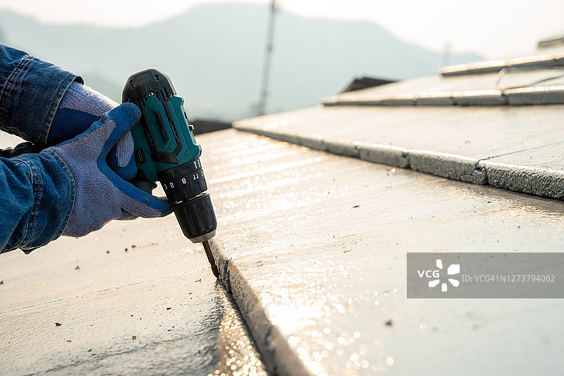 屋顶工人在屋顶上用手钻安装新屋顶图片素材