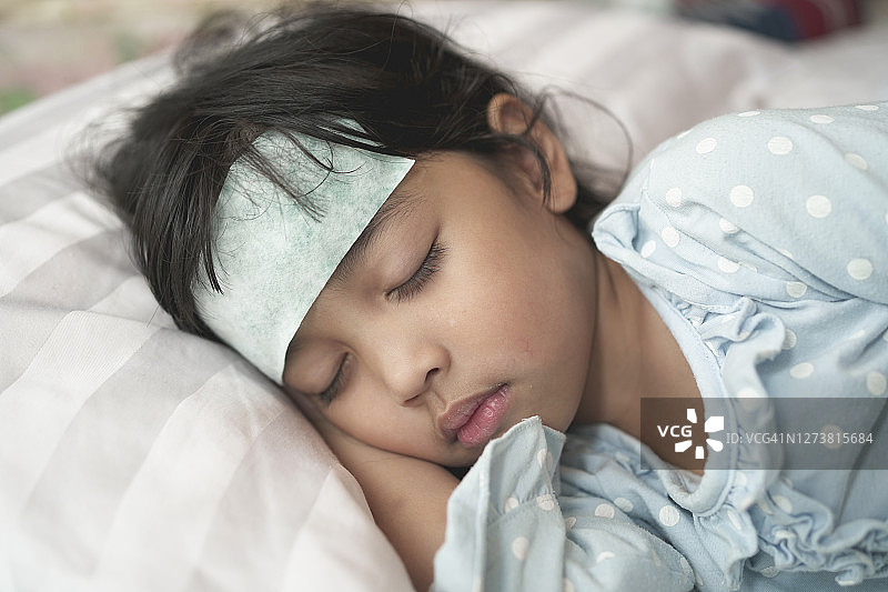 在医院接受病毒治疗的亚洲患儿。额头上贴着退热贴图片素材