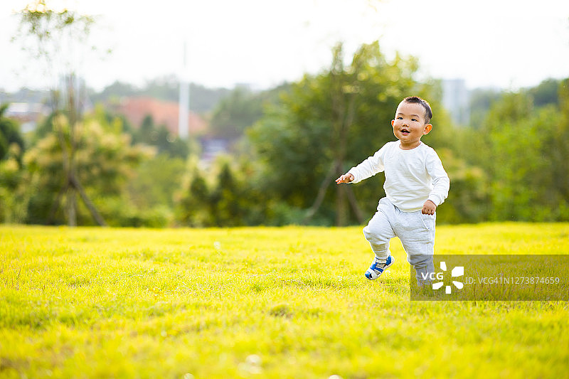 秋天里在草坪上奔跑的男婴图片素材