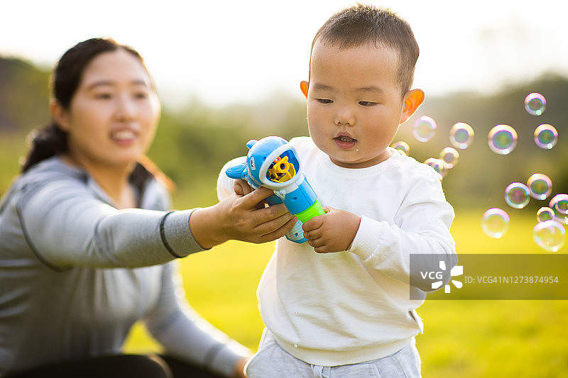 妈妈和男宝宝在公园里吹肥皂泡图片素材