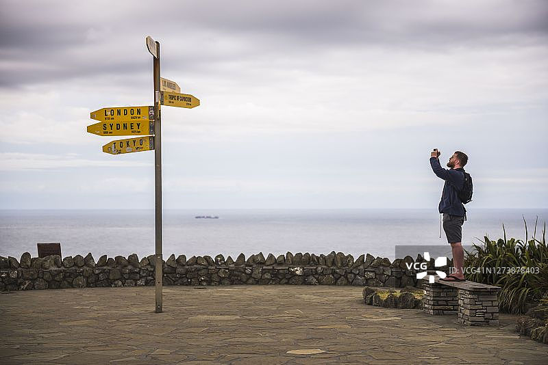 游客在新西兰雷因加角灯塔拍摄城市距离指示牌图片素材