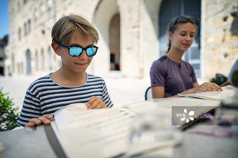 兄妹在沃尔泰拉街边餐厅享用披萨午餐图片素材
