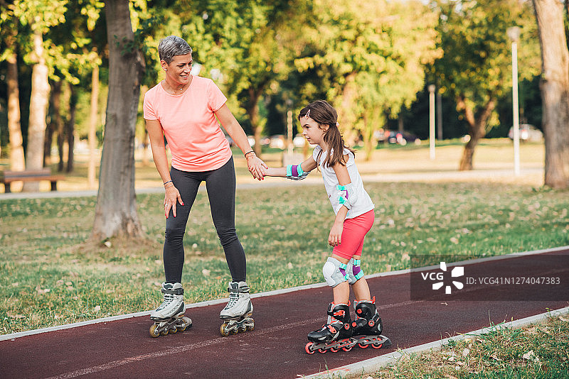 母亲帮助女儿学习滑旱冰图片素材