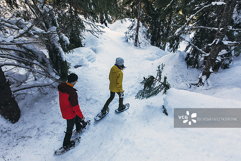 一对情侣在树林里穿着雪鞋健行图片素材