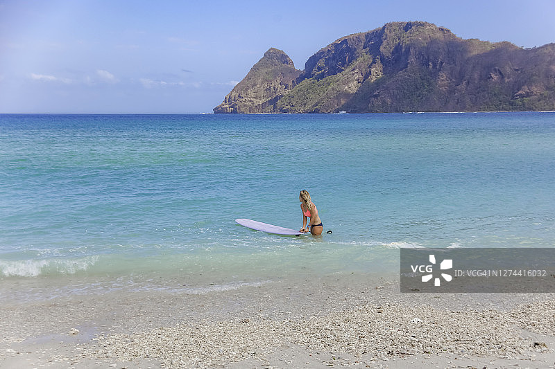 女人带着冲浪板进入印度尼西亚松巴哇岛的海洋图片素材