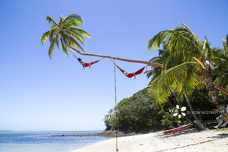 在斐济科罗莱武，两名男子在吊床上放松身心图片素材