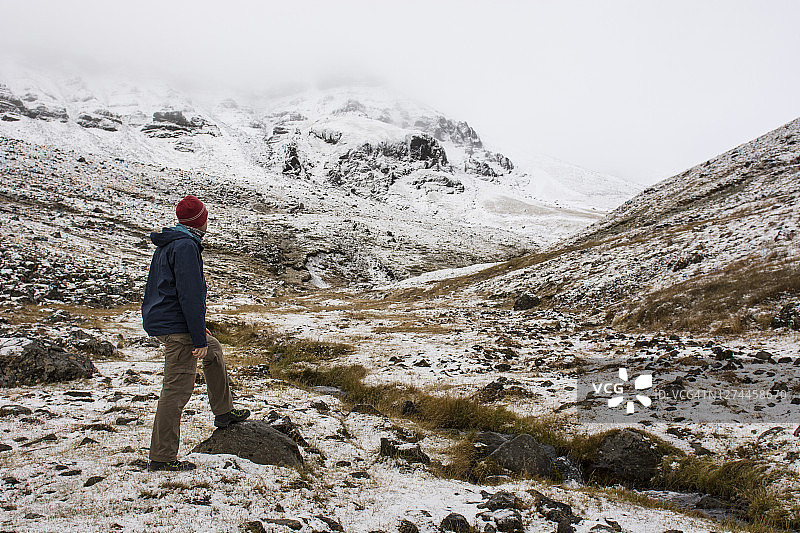 年轻男子在冰岛基亚拉内斯埃斯亚山欣赏雪山风光图片素材