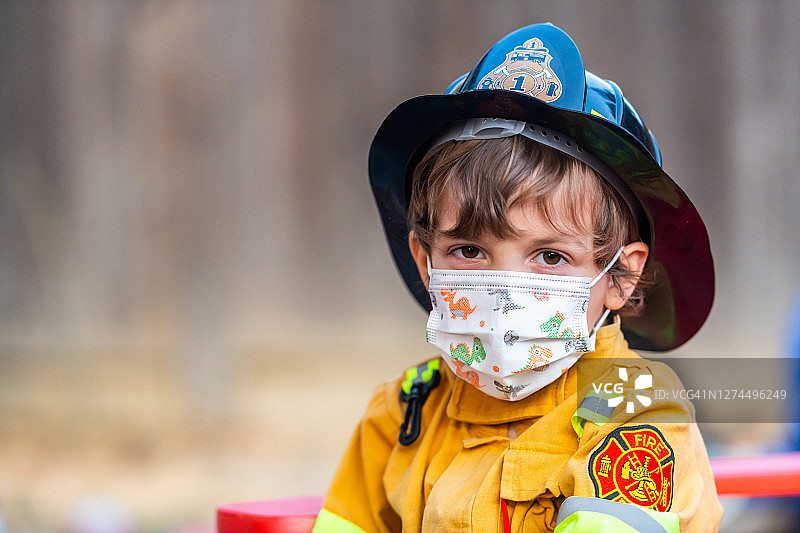 万圣节消防员装扮的严肃小男孩戴着防护口罩看着镜头图片素材