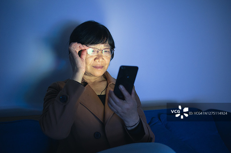 亚洲老年妇女坐着看手机图片素材