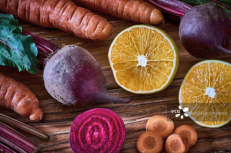 准备烹饪的木板上的胡萝卜、甜菜根和橙子图片素材