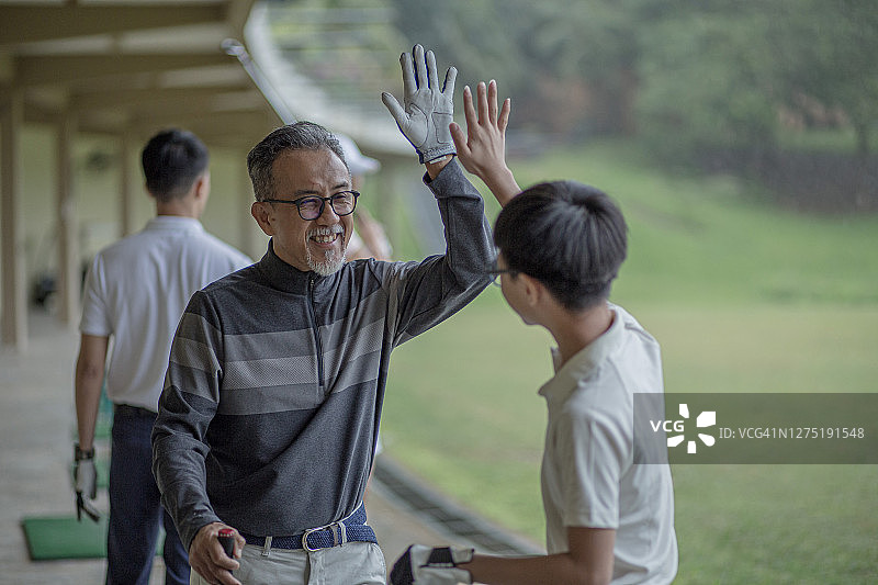 中国亚洲爷爷指导孙子练习高尔夫图片素材