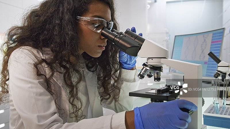 实验室里的多种族科学家，混血女人位于前景，电脑屏幕上的脑电波扫描研究图片素材