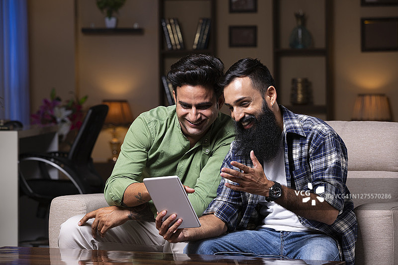 年轻的朋友坐在家里的沙发上-库存照片图片素材