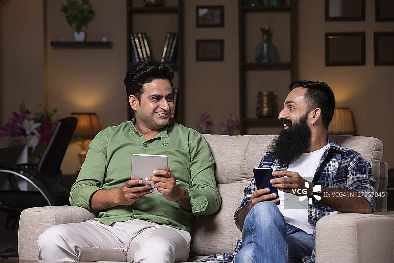 年轻的朋友坐在家里的沙发上-库存照片图片素材