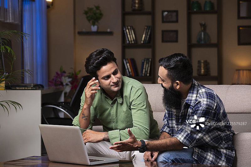 年轻的朋友坐在家里的沙发上-库存照片图片素材