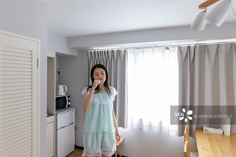 年轻女子穿着睡衣在房间里刷牙图片素材