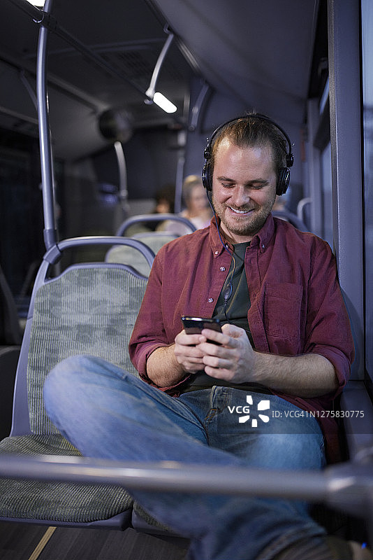 男人在巴士内戴着耳机用智能手机听音乐图片素材
