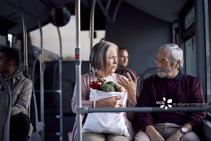 老夫妇在公交车内拿着食品购物袋图片素材