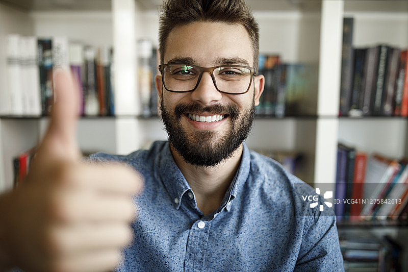 年轻男子在家办公时竖起大拇指图片素材