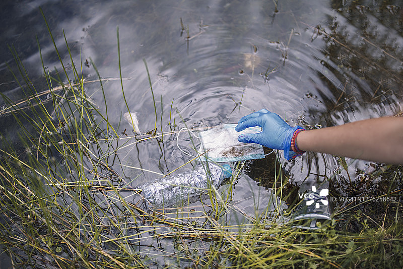负责任的人正在清理人们使用后遗留在自然环境中的防护口罩图片素材