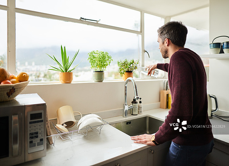 年轻男人在家中窗台上浇花图片素材