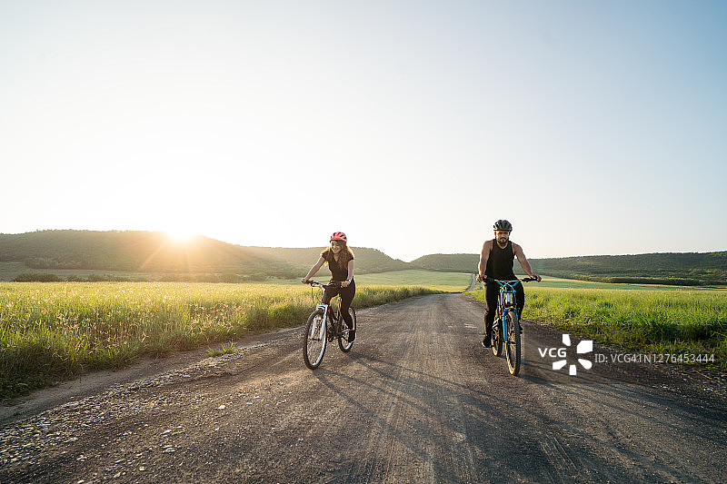 日出时分在乡间骑自行车的两位拉丁裔人图片素材