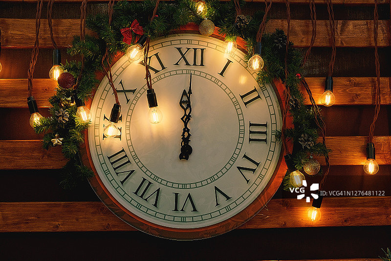 复古手表的表盘设置为除夕夜的十二点，装饰着发光灯泡和花环图片素材