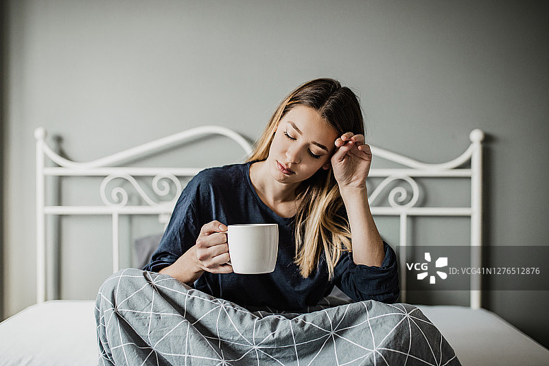 坐在床上的悲伤的年轻疲惫的女人图片素材