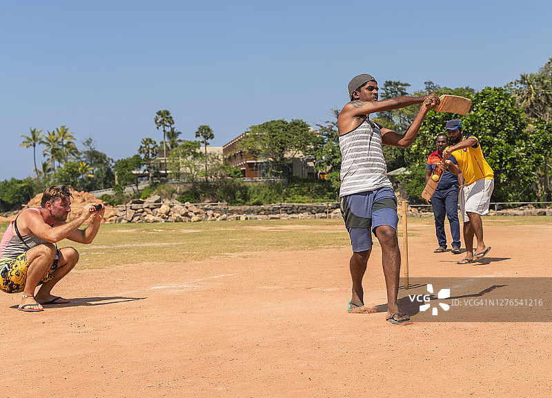 在斯里兰卡拍摄街头板球队比赛的白人游客图片素材