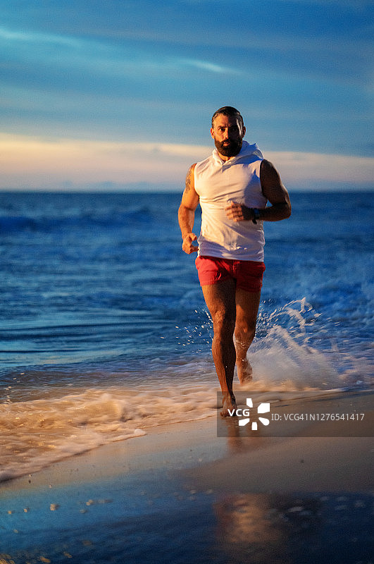 在美国佛罗里达州日落时在海滩上跑步的男人图片素材